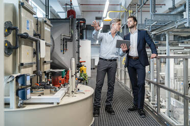 Two businessmen with tablet talking in a modern factory - DIGF07657