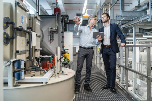 Zwei Geschäftsleute mit Tablet im Gespräch in einer modernen Fabrik - DIGF07657