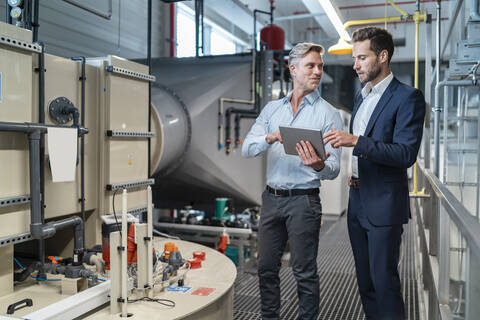 Two businessmen with tablet talking in a modern factory stock photo