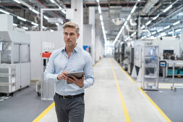 Businessman using tablet in a modern factory - DIGF07663