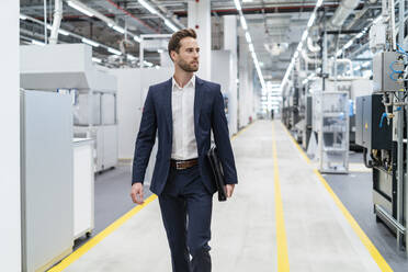 Businessman walking in a modern factory - DIGF07665