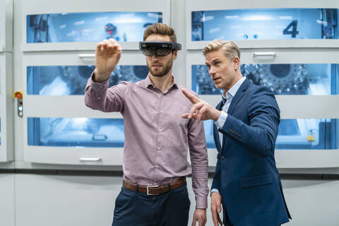 Two businessmen with AR glasses in a modern factory stock photo