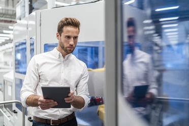 Businessman using tablet in a modern factory - DIGF07702