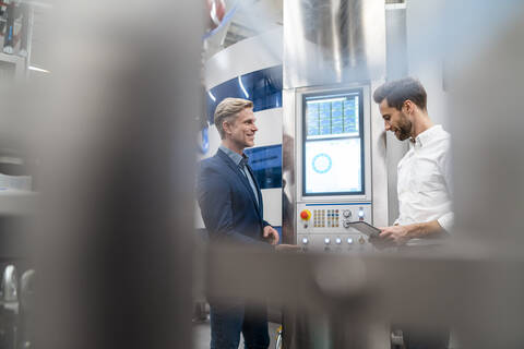 Zwei Geschäftsleute im Gespräch in einer modernen Fabrik, lizenzfreies Stockfoto