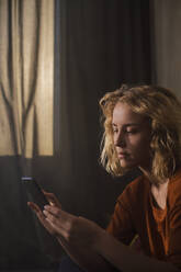 Portrait of blond young woman using cell phone - GCF00296