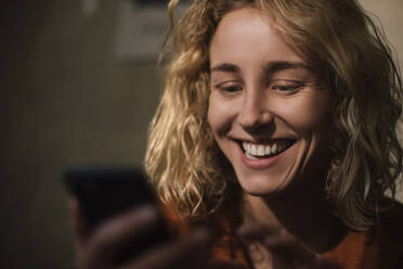Porträt einer blonden jungen Frau, die ein Mobiltelefon benutzt - GCF00299