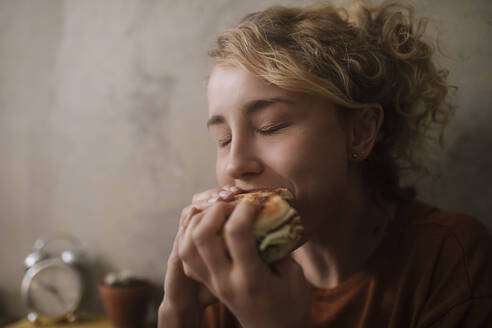 Portrait of young woman eating Hamburger - GCF00311