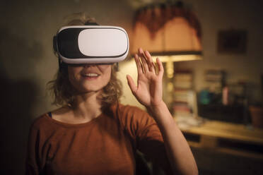 Junge Frau benutzt eine Virtual-Reality-Brille zu Hause - GCF00317