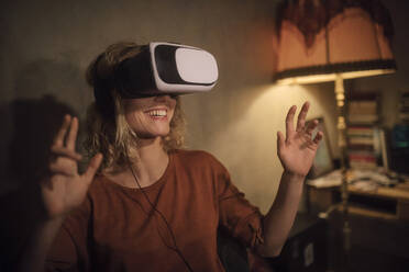 Junge Frau benutzt eine Virtual-Reality-Brille zu Hause - GCF00319