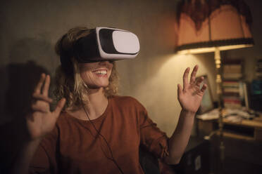 Young woman using Virtual Reality Glasses at home - GCF00319