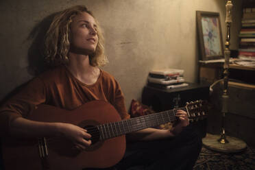 Junge Frau spielt Gitarre zu Hause - GCF00329