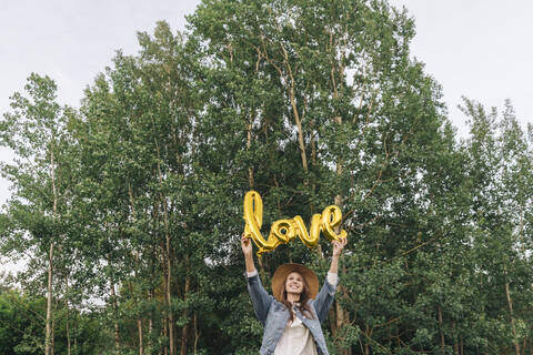 Junge Frau hält das Wort Liebe in einem Wald, lizenzfreies Stockfoto