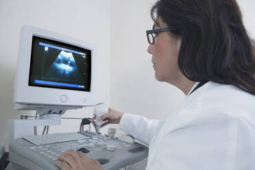 Hispanic doctor examining sonogram in hospital - BLEF10240
