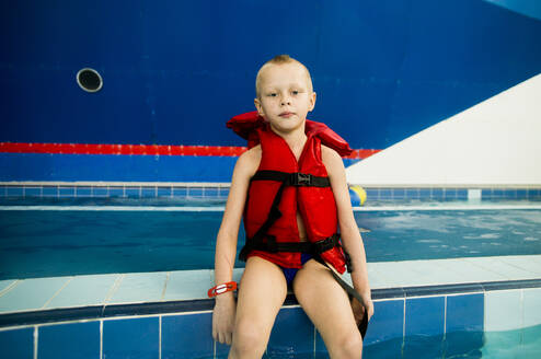 Kaukasischer Junge mit Schwimmweste im Schwimmbad - BLEF10280