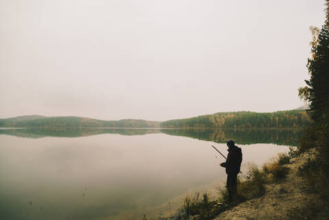 Mann fischt in abgelegenem See, lizenzfreies Stockfoto