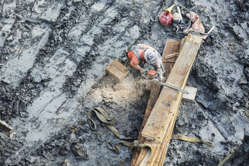 Weißer Arbeiter sägt Holz auf einer Baustelle - BLEF10301