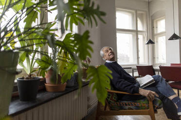 Senior man sitting on chair at home - GUSF02058