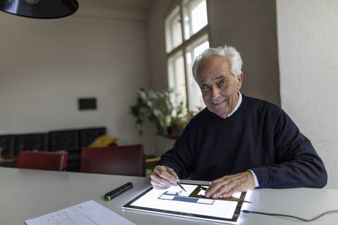 Porträt eines lächelnden älteren Mannes, der ein Tablet mit einem Architekturplan benutzt, lizenzfreies Stockfoto