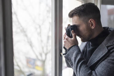 Junger Mann beim Fotografieren am Fenster - GUSF02070