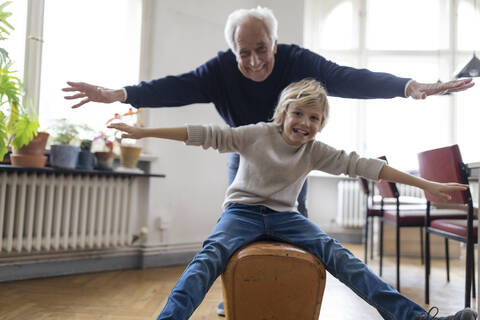 Happy grandfather and grandson playing with buck at home stock photo