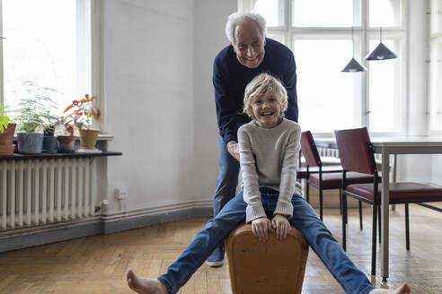 Happy grandfather and grandson playing with buck at home - GUSF02073