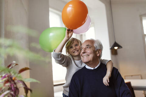 Happy grandfather and grandson playing with balloons at home stock photo