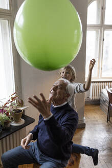 Happy grandfather and grandson playing with balloon at home - GUSF02090
