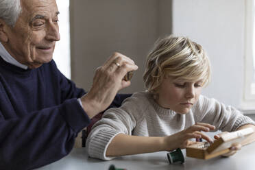 Watchmaker and his grandson examining watch together - GUSF02092