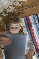 Top view of boy lying on carpet using tablet - GUSF02114