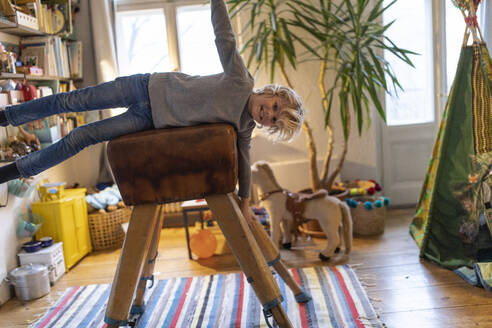 Portrait of smiling boy lying on buck in his room at home - GUSF02123