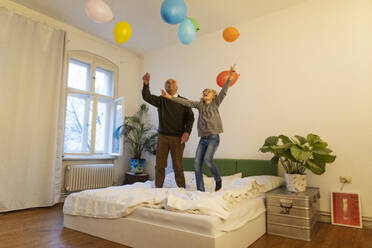 Glücklicher Großvater und Enkel spielen mit Luftballons auf dem Bett zu Hause - GUSF02130