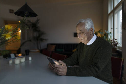 Smiling senior man using tablet at home - GUSF02131