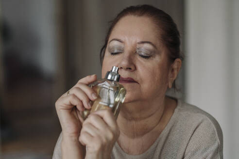 Senior woman smelling at perfume flacon - GUSF02137