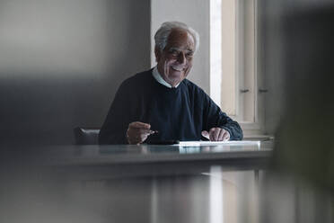 Portrait of smiling senior man using tablet at home - GUSF02139