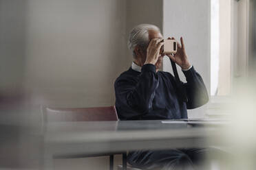 Senior man at home with cardboard VR glasses - GUSF02150