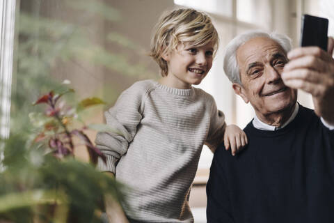 Happy grandfather and grandson taking a selfie at home stock photo