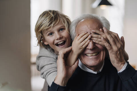 Glücklicher Enkel spielt mit Großvater zu Hause, lizenzfreies Stockfoto