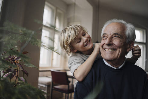 Happy grandson pulling grandfather's ears at home - GUSF02170