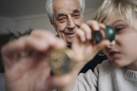 Watchmaker and his grandson examining watch together stock photo