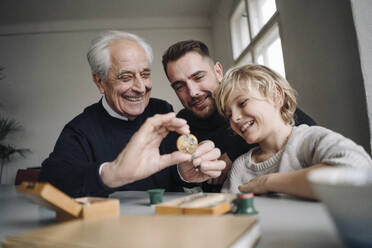 Happy watchmaker showing clockwork to young man and boy - GUSF02178