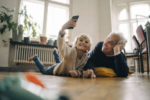 Großvater und Enkel liegen zu Hause auf dem Boden und machen ein Selfie - GUSF02181