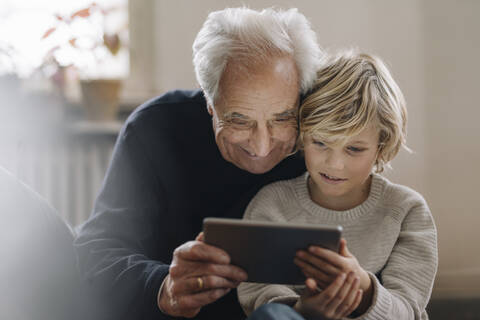 Grandfather and grandson using a tablet at home stock photo