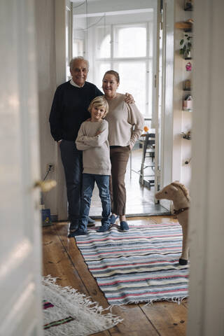 Porträt von glücklichen Großeltern mit Enkel zu Hause, lizenzfreies Stockfoto