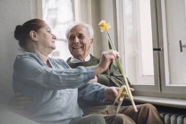 Glückliches Seniorenpaar mit Blume zu Hause - GUSF02202