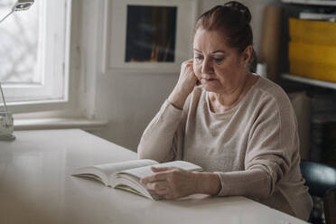 Senior woman reading book at home - GUSF02228