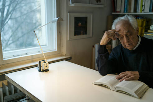 Älterer Mann liest zu Hause ein Buch - GUSF02237