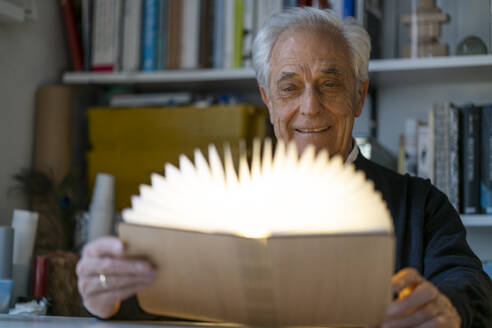 Senior man with glowing book at home - GUSF02239