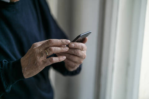 Close-up of senior man using cell phone at home stock photo