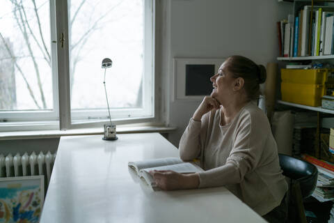 Happy senior woman reading book at home stock photo