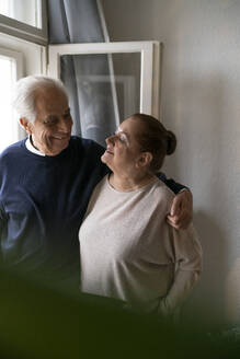 Happy senior couple at the window at home - GUSF02259